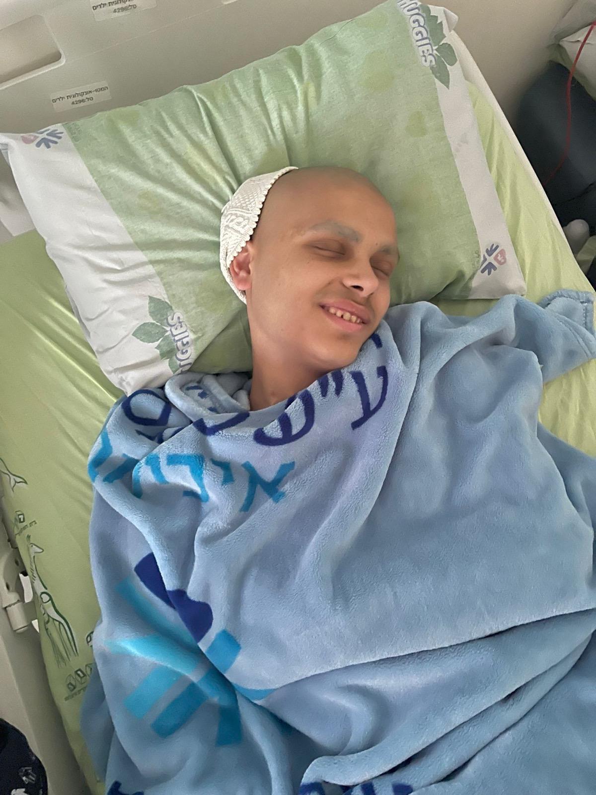 נער שוכב במיטת בית חולים מכוסה בשמיכה