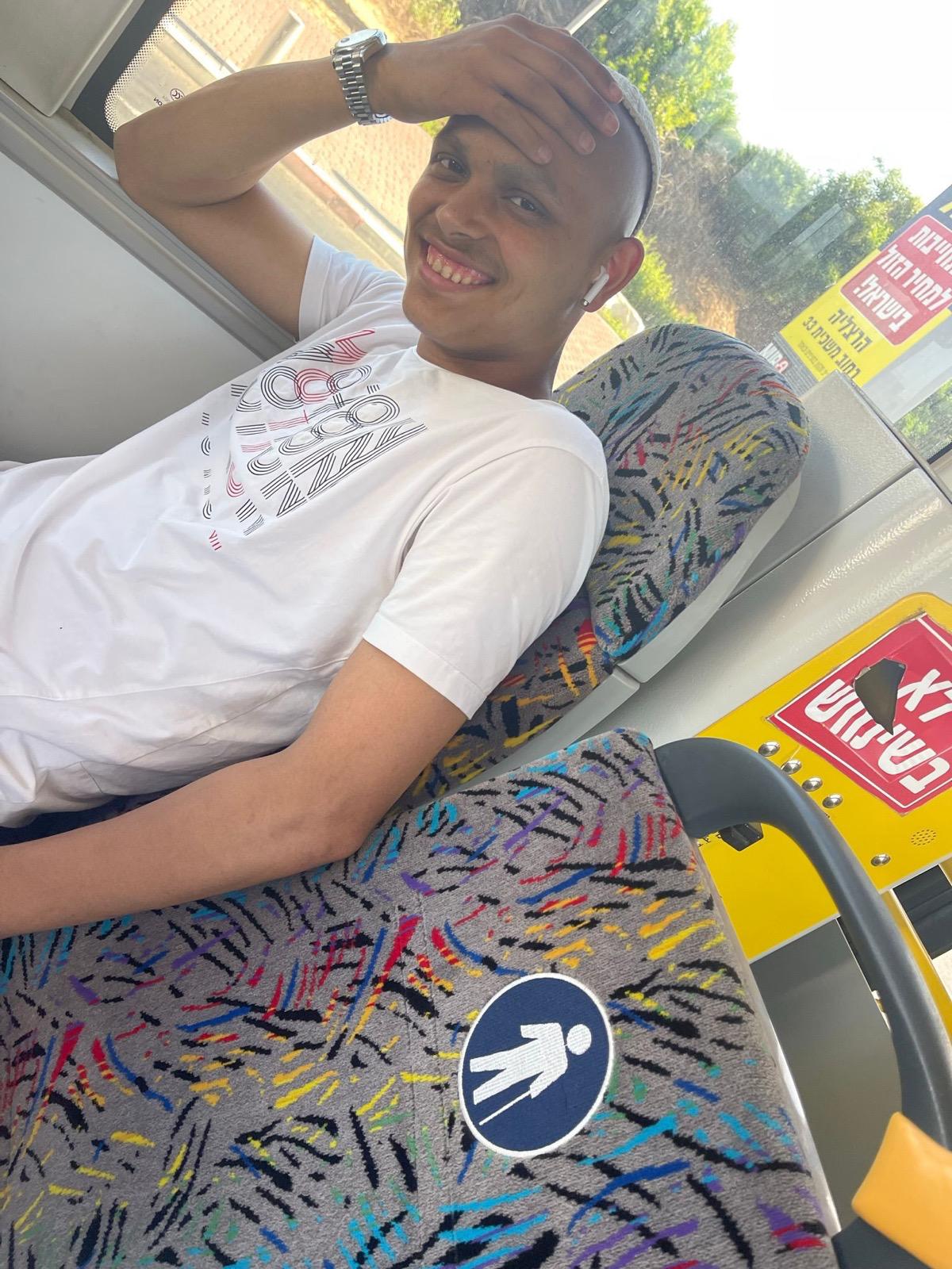 נער מחייך יושב במושב באוטובוס