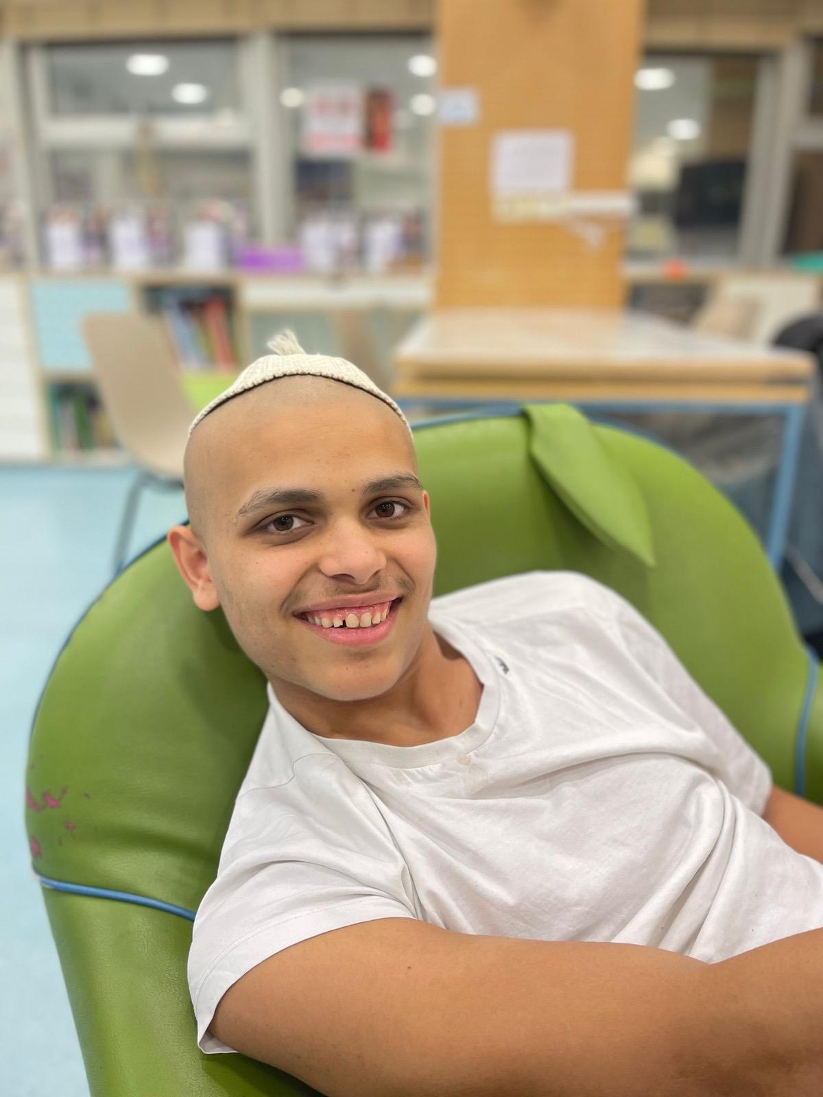 נער יושב בכורסה ירוקה בבית החולים